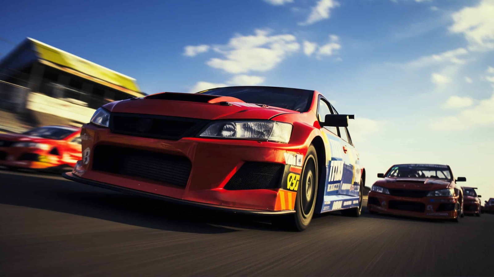 Berline de course rouge et blanche à aileron, lancée en tête devant plusieurs concurrentes sur un circuit sous un ciel bleu