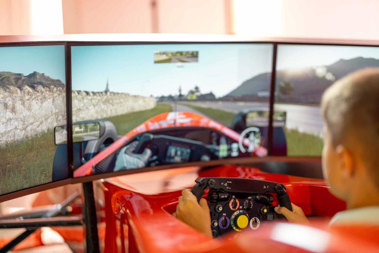 Pilote dans un cockpit formule rouge, mains sur une jante de type formule, triple écran affichant un circuit