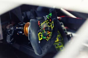 Gros plan sur le volant d'une voiture de course, moyeu à attache rapide à bague orange et câble spiralé visibles