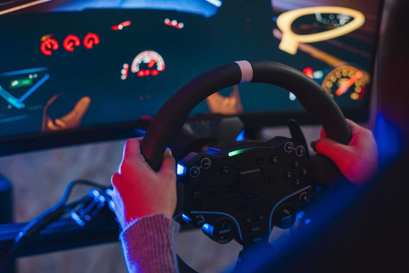 Deux mains sur la jante d'un volant simracing marquée en son sommet, tableau de bord affiché à l'écran