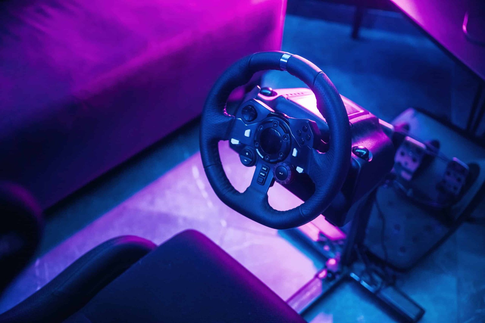 Volant de simracing et pédalier installés dans une pièce éclairée par des néons violets et bleus