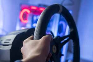 Main sur la jante perforée d'un volant simracing, repère clair visible en haut de la jante, néon rouge en arrière-plan