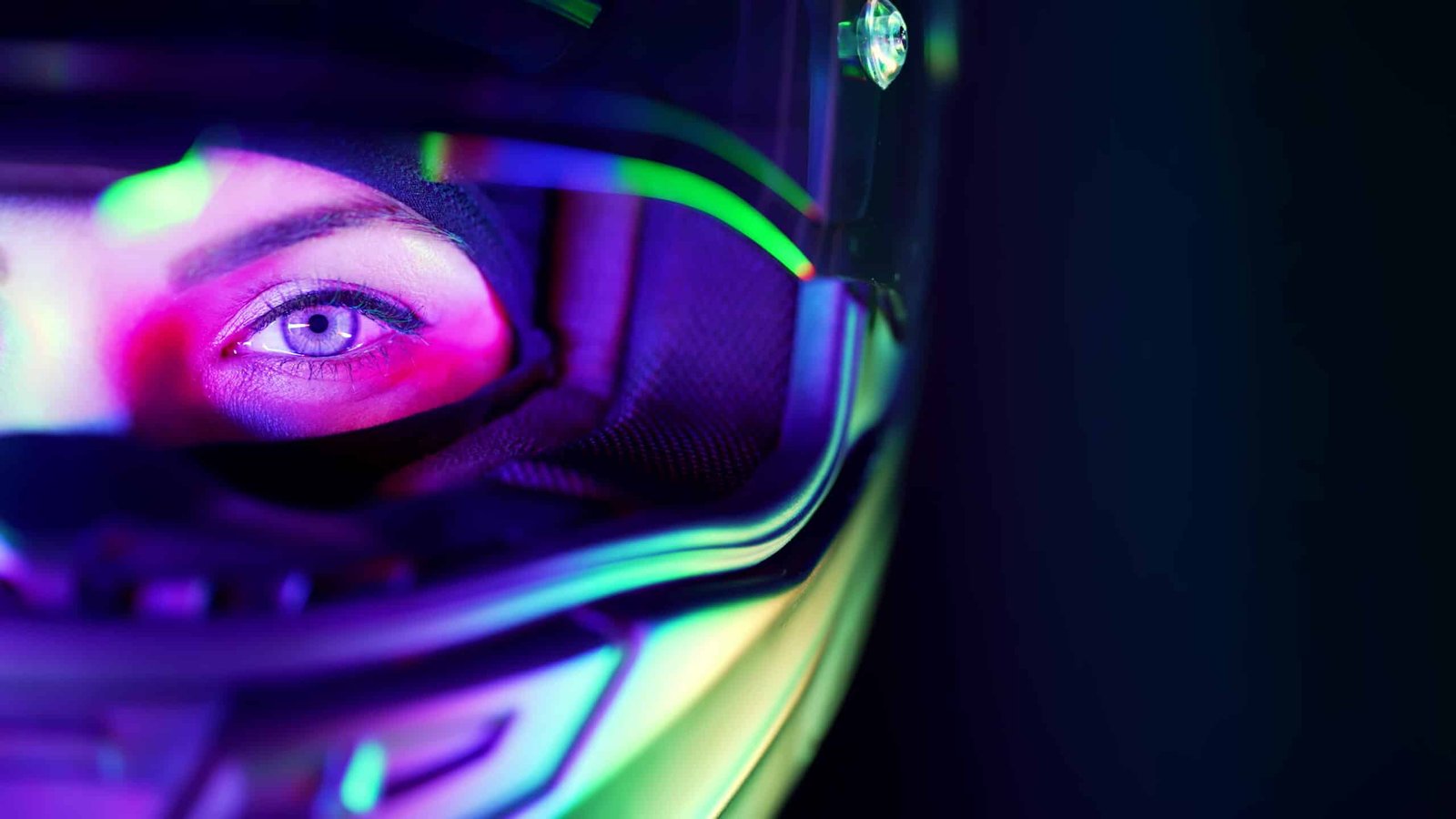 Gros plan sur l'œil d'un pilote derrière la visière d'un casque de course, reflets de néons verts et roses