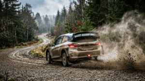 Voiture de rallye boueuse en glisse sur une piste de gravier en forêt, gravillons projetés par les roues arrière