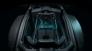 Vue plongeante dans un cockpit de simracing à coque en carbone façon monoplace : baquet noir, volant de formule sur sa base et pédalier au fond, sous un éclairage cyan