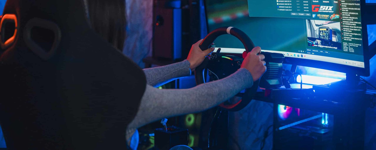 Pilote vu de dos, les deux mains sur un volant simracing rond, face à un écran affichant une interface de jeu de course, éclairage bleu