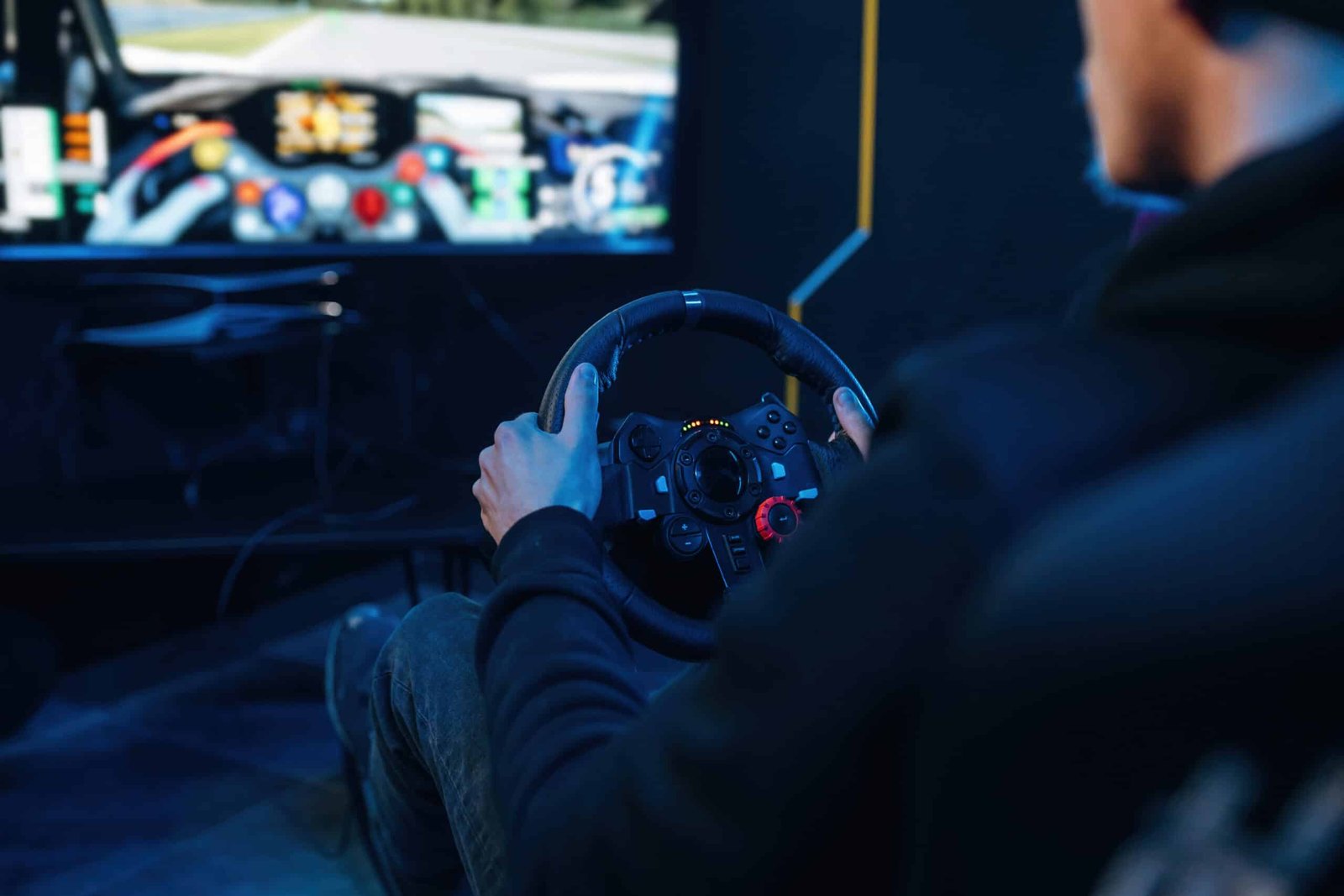 Pilote une main sur la jante d'un volant simracing, écran affichant la vue intérieure d'une voiture de course