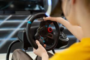 Pilote les deux mains sur la jante d'un volant simracing à retour de force, levier de vitesse à droite