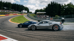 Deux voitures de course GT côte à côte en appui dans une courbe, la grise à l'extérieur de la bleue, tribunes en fond